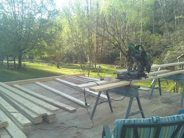 Miter saw and framing lumber on a deck under construction in Logan